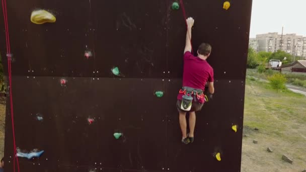 산악인의 공중 트랙 야외 인공 벽 등반 속도 록을 실행 합니다. 젊은 빠른 선수는 대회에서 절벽을 올라. 하네스를 걸이에 남자 bouldering 챔피언십에서 수행. — 비디오