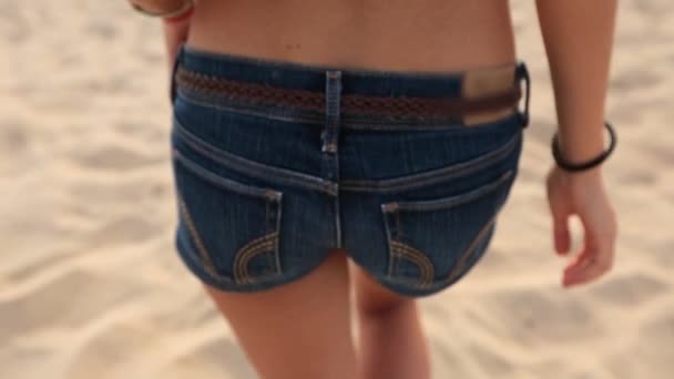 Close back view of young pretty woman butt and leg wearing blue jean shorts. Girl with slim body and ass walking on sandy tropical beach enjoying summer vacation. Rear view slow motion. — Αρχείο Βίντεο