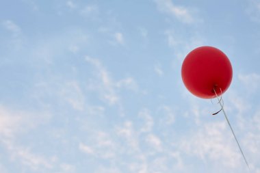 Arka plan üzerinde kırmızı helyum hava balonu sakin mavi bulutlu gökyüzü ile. Barış ve tatil kavramı. Alt görünümü. Boşaltmak için minimalist tasarım.