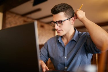 Dizüstü bilgisayarda çalışarak bardaklarda düşünceli genç beyaz işadamı. Dalgın çekici hipster freelancer çizik olanlar baş ve sorunun çözümü üzerinde düşünüyor. İş kavramı.