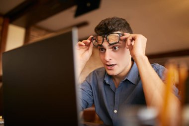 Sürpriz freelancer hipster adam dizüstü bilgisayar ekranına bakar ve o yeşil kart vize veya piyango Ödülü kazandı inanamıyorum. Miken'de başarılı hayran işadamı tüccar olanları gözleri gözlük yükseltir