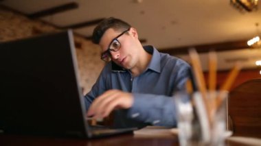 Kahve içme ve bir pasta yemeye not defterinde, notlar ve arama bilgi alarak Evet bezgin yakışıklı genç işadamı bardaklarda dizüstü bilgisayar, çalışma. Çoklu görev telecomuting kavramı.