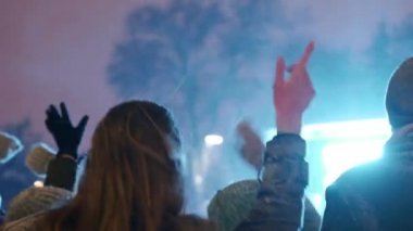 Gençler şehir meydanındaki Noel konserinde parti yapıyorlar. Arkadaşlar el sallayarak ve kollarıyla dans ederek yeni yıl piyasa müzik sahnesinde zıplarken iyi eğlenceler. Kış gecesi kar yağışıweather forecast.