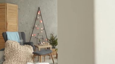 Bir şık koltuk ve sıcak merinos ekose ile şık Noel İskandinav iç. Konfor nordic Yılbaşı dekor ile ev. Çelenk ve ışık oda ışıkları ile minimalist Noel ağacı.