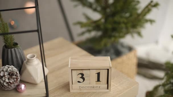 Stijlvolle kerst Scandinavische interieur details. Comfort thuis met de Noordse oud & nieuw decor. Spar takken in een vaas, houten kubus kalender met 31 December cijfers en minimalistische kerstboom — Stockvideo