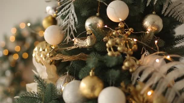 Stijlvolle witte kerst interieur met versierde sparren. Comfort home met kerstboom vol met gouden decoraties, met krans en lichten van slingers op achtergrond. New Years Eve. — Stockvideo