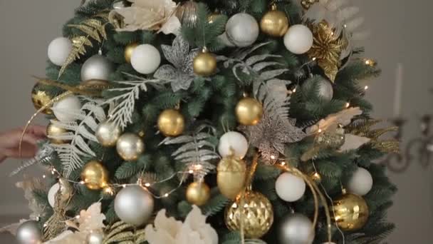 Elegante diseño interior blanco de Nochevieja con abetos decorados. Casa confortable con árbol de Navidad lleno de decoraciones doradas, luces y guirnaldas y lámparas . — Vídeo de stock