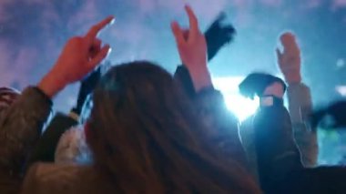 Gençler şehir meydanındaki Noel konserinde parti yapıyorlar. Arkadaşlar el sallayarak ve kollarıyla dans ederek yeni yıl piyasa müzik sahnesinde zıplarken iyi eğlenceler. Kış gecesi kar yağışıweather forecast.
