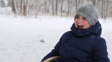 Karlı kış gününde mutlu aile kızakları. Kızları, karlı bir günde anne ve babasının oğluyla kızak çekmesine yardım ediyor. Erkek dışarıda kızakla kayıyor. İnsanlar kızağa biniyor ve Noel tatilinin tadını çıkarıyor. Jumpsiut giyen kız..
