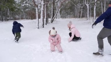 Baba, anne, oğul ve küçük kız karlı bir günde ormanda kartopu oynuyorlar. Arkadaş canlısı stil sahibi aile ormanda kar atarken eğlenir. İnsanlar kış tatilini birlikte severler. Yavaş çekim.