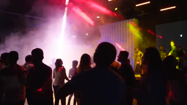 Mariupol, Oekraïne - 15 juni 2019. Mensen dansen in Barbaris nachtclub verlicht door schijnwerpers. Silhouetten van mannen en vrouwen die feesten op de dansvloer in slow motion. Gewone open entree weekend feest. — Stockvideo