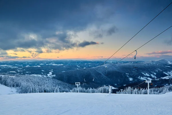 Paisaje nocturno de invierno en las montañas con bosque de abetos al atardecer. Colinas cubiertas de nieve después de fuertes nevadas. Snowy backcountry esquí pistas escenografía. Dramáticas nubes en el horizonte al amanecer . —  Fotos de Stock