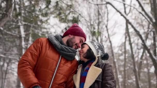 Joven pareja amorosa caminando en un parque en las nevadas. Hombre y su novia tomados de la mano disfrutando de la nieve en el día de invierno. Hipster mujer paseo en el bosque nevado sonriendo con novio en ropa elegante . — Vídeos de Stock