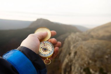 Kâşif adamın elinde altın pusula, elinde sonbahar dağları arka planıyla yönünü ararken çekilmiş bir fotoğraf.
