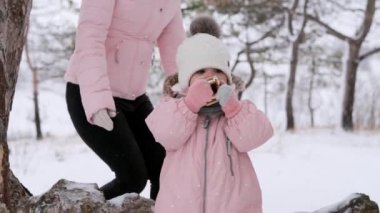 Pembe tulumlu küçük kız, karlı bir günde kızakla kaydıktan sonra Noel kurabiyesi yiyor. Güzel bir aile kış tatilini birlikte geçirir. Şefkatli anne ve baba kompozisyonda gelirler, sarılırlar, çocuğu öperler..