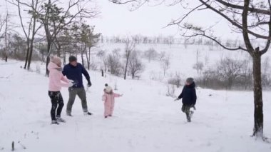 Baba, anne, oğul ve küçük kız karlı bir günde ormanda kartopu oynuyorlar. Arkadaş canlısı stil sahibi aile ormanda kar atarken eğlenir. İnsanlar kış tatilini birlikte severler. Yavaş çekim.