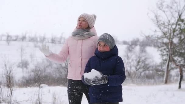 Padre, madre, figlio e figlioletta giocano a palle di neve nel bosco il giorno nevoso. Amichevole famiglia elegante divertirsi con gettare la neve nella foresta. Alla gente piacciono le vacanze invernali insieme. Rallentatore . — Video Stock