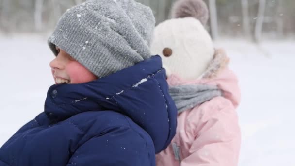 Feliz familia en trineo el día de invierno nevado. Bebé empuja trineo en las nevadas. Muchacho trineo al aire libre. Hermosa escena linda con hermana y hermano. Niña en traje rosa cálido disfrutar de la temporada de Navidad . — Vídeo de stock