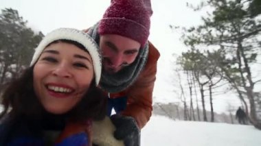 Kış günü kızakla kayan güzel çiftin selfie videosu. Adam, kız arkadaşıyla kızağı kar yağarken itiyor. Kadınlar dışarıda kameralı sevgilileriyle eğlenip kızak çekerler. İnsanlar kızağa biniyor ve video çekiyor.