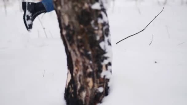 Kvinnliga fötter i svarta läderstövlar som går i en park på snöfall. Kvinnan trampar snö njuter av jullovet. Lång vinkel sida spårning skott av flicka promenad i skogen på snöig vinterdag. — Stockvideo