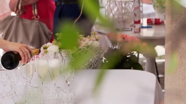 Ober schenkt champagne in op glazen tijdens een feest in het restaurant buiten. Sprankelend wit gejammer op verjaardagsfeestje of bruiloftsbuffet. — Stockvideo