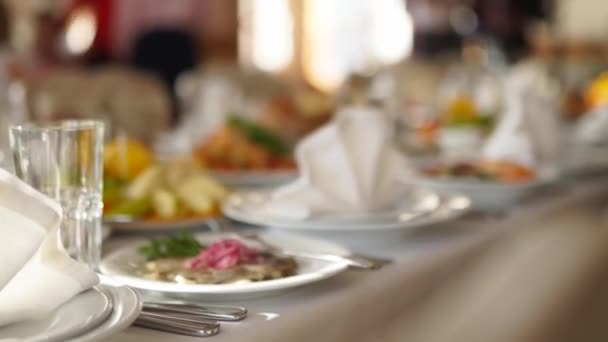 Krásně servírovaný banketový stůl s různými jídly občerstvení a předkrmy na slunci na firemní vánoční večírek nebo svatební oslavu. Dekorovaný catering v bílém interiéru. — Stock video