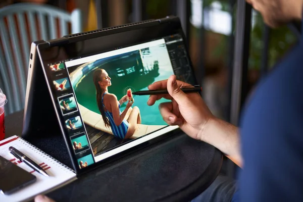 Freelancer ritoccatore uomo lavora su computer portatile convertibile con software di fotoritocco utilizzando stilo. Fotografo o designer artista digitale elaborazione delle immagini. 2 in 1 con touch screen in modalità tenda . — Foto Stock