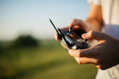 Adam uzaktan kumandayı elinde tutuyor. Uçuş sırasında Quadrocopter Rc 'ye yakın çekim. Pilot dörtlü ile hava fotoğrafları ve videolar çeker