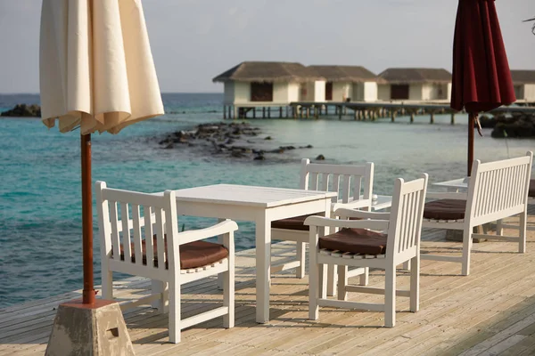 White empty table table and chairs at tropical resrraunt on open terrace in maldives. Blue ocean lagoon on background. No people. — Stock Photo, Image