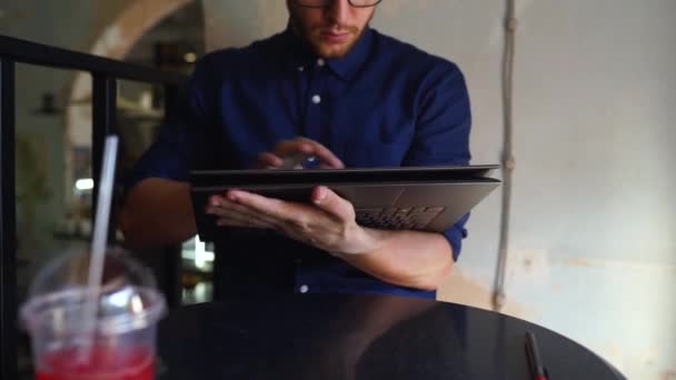 L'uomo freelancer trasforma il computer portatile convertibile in modo di targa e lavora con touchscreen. Artista digitale utilizzare 2 in 1 computer con digitalizzatore touch screen per rendere il suo progetto di business in caffè . — Video Stock