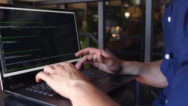 Vista posterior sobre la toma de hombro del programador desarrollador con computadora portátil. Código de programa y datos de script en la pantalla. Joven freelancer en gafas trabajando en proyecto en cafetería . — Vídeos de Stock