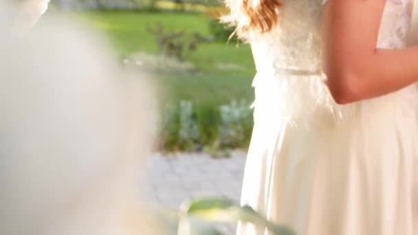 Близко изолированная сцена, где женихи нежно обнимают невест за талию. Золотое обручальное кольцо на пальце молодоженов. Подсветка сцены с солнечными вспышками на теплом летнем закате снаружи . — стоковое видео