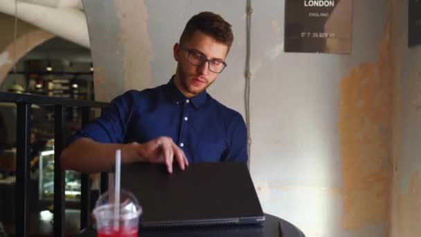 Ung frilansare man öppnar och börjar använda laptop med biometriska ansiktsigenkänning system på kontoret. Utvecklaren börjar sin fjärrarbetsdag på caféet. Dator med ansiktsidentifiering. — Stockvideo