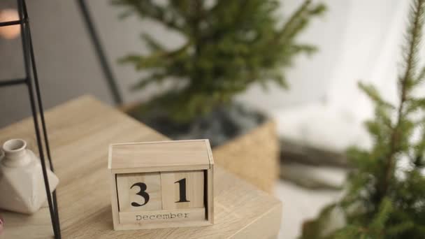 Stylish christmas scandinavian interior details. Comfort home with nordic new years eve decor. Fir branches in vase, wooden cube calendar with December 31st figures and minimalistic christmas tree — Stock Video