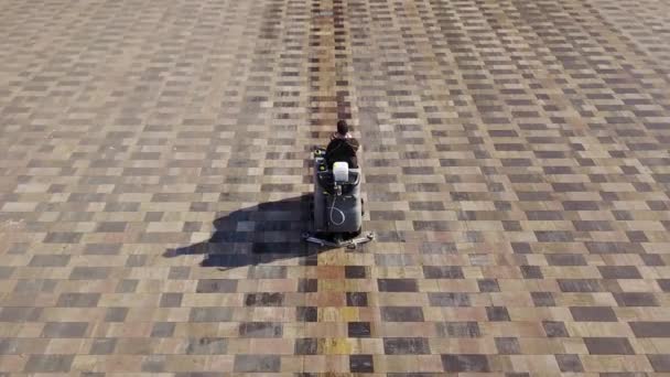 Aerial view of compact street sweeper car cleaning city sidewalk paving slabs with high pressure washers and rotating brooms outdoors. Road sweeping machine janitor leaves wet footprint on square. — Stock Video