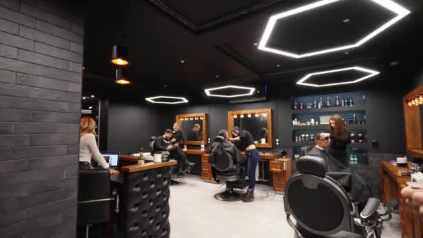 Point of view shot of hipster barber throwing a hair cloak on the client with transition to black. Hairdresser puts on cape on camera in barber shop, POV. Trendy coiffeur at work in retro hair salon. — Stock Video