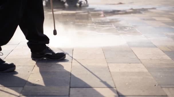 Stadsstraten schoonmaken met waterdrukwasser. De conciërge sprays stad straat stoep plavuizen. Werknemer desinfecteert vloer en oppervlakken van coronavirus. Antibacteriële sanitaire maatregelen inzake quarantaine — Stockvideo