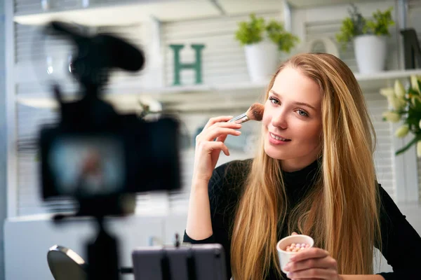 Beauty blogger woman filming daily make-up routine tutorial near camera on tripod. Influencer girl live streaming cosmetics product review in home studio. Vlogger female applies skin powder with brush — Stock Photo, Image