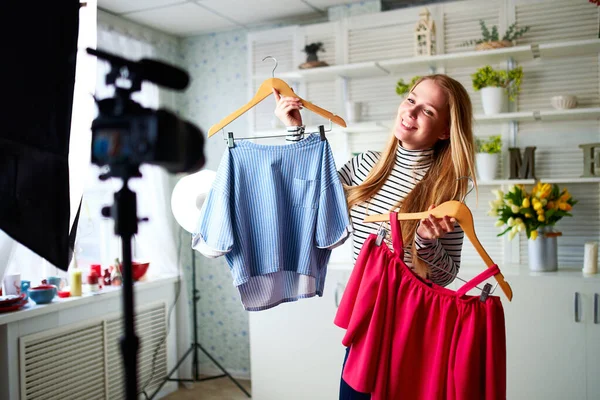 Mode bloggare kvinna i jeans och polotröja visar casual färgglada skjortor på kameran. Stylist influencer flicka visar trendiga kläder filmar vlog episod för hennes kanal. Opinionsledare sätter trender. — Stockfoto
