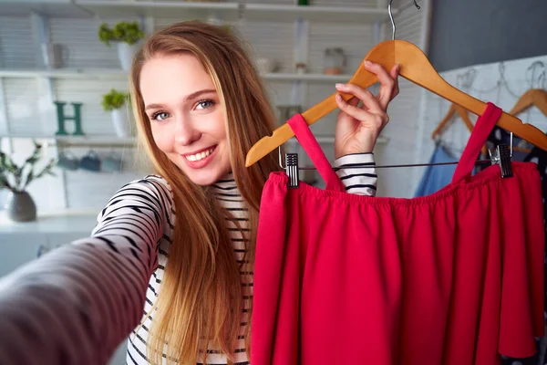 Fashion blogger woman in jeans and turtleneck showing casual colorful shirts on camera. Stylist influencer girl showing trendy clothes filming vlog episode for her channel. Opinion leader sets trends. — Stock Photo, Image