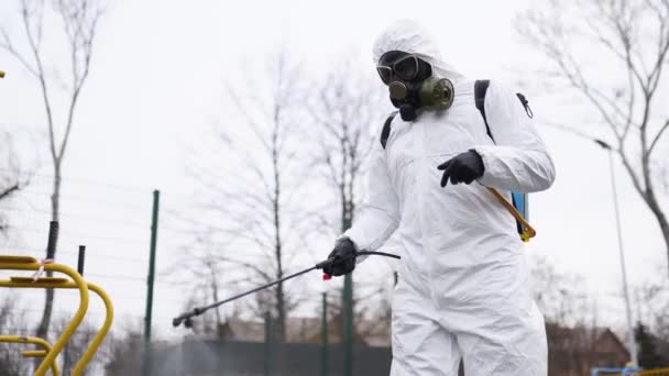 Tehlikeli madde işçisi, karantinada antibakteriyel dezenfektanla Coronavirus covid 19 'un spor zeminini dezenfekte ediyor. Koruyucu takım elbiseli adam kamu spor malzemelerini temizliyor.. — Stok video
