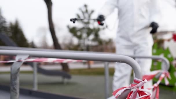 Sanitizer desinfecteert railing touch oppervlakken op coronavirus covid-19 quarantaine met antibacteriële sproeier. Werknemer in gasmasker en hazmat beschermend pak reinigt leuningen in de stad openbare plaats. — Stockvideo