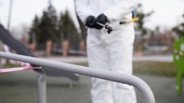 Sanitizer disinfects railing touch surfaces on coronavirus covid-19 quarantine with antibacterial sprayer. Worker in gas mask and hazmat protective suit cleans handrails in city public place. — Stock Video