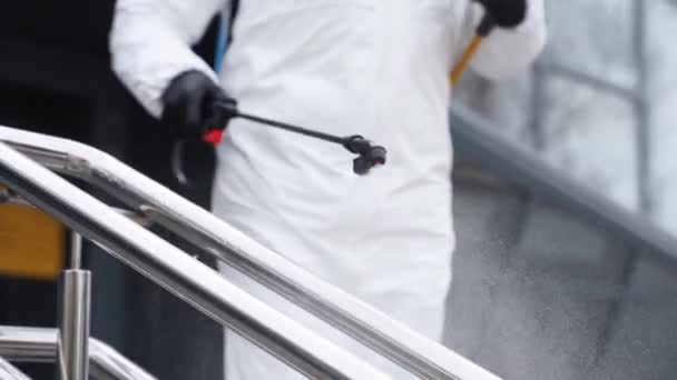 Sanitizer disinfects railing touch surfaces on coronavirus covid-19 quarantine with antibacterial sprayer. Worker in gas mask and hazmat protective suit cleans handrails in city public place. — Stock Video