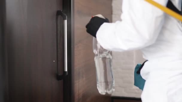 Στενή θέα του χεριού στο ιατρικό γάντι χρησιμοποιώντας αντιβακτηριακό ψεκαστήρα, σκουπίστε για απολύμανση πόμολο πόρτας. Απολύμανση και καθαρισμός πορτών. Νεογνά, βακτήρια, Covid-19, SARS, πανδημία του κορωναϊού. — Αρχείο Βίντεο
