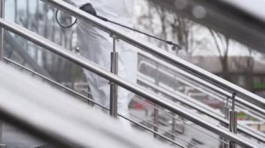 Antibakteriyel spreyle koronavirüs covid-19 karantinasının tırabzan dezenfekte yüzeyini dezenfekte eder. Gaz maskeli ve koruyucu giysili işçiler şehrin kamusal alanındaki tırabzanları temizliyor..