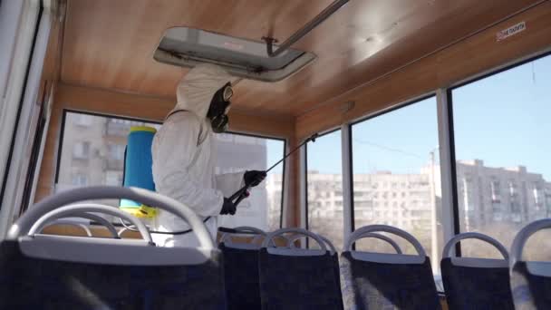 Hazmat team medewerker desinfecteert busstoelen met antibacteriële ontsmettingsspray op coronavirus covid-19 quarantaine. Man met gasmasker, hazmat pak reinigt het openbaar vervoer interieur, handgrepen met wasmachine. — Stockvideo