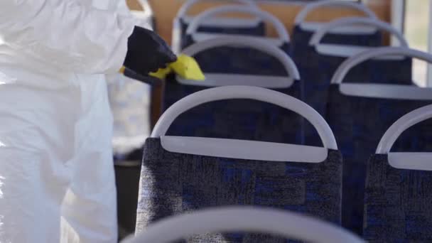 Hazmat team medewerker desinfecteert bus interieur met antibacteriële reinigingsmiddel doekjes op coronavirus covid-19 quarantaine. Man met gasmasker, hazmat pak reinigt openbaar vervoer stoelen, handgrepen met vod. — Stockvideo