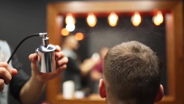 Barber sprays parfume on client in barbershop after haircut and styling. Hairdresser using old fashined sprayer with toilet water in hair salon after customers beard shaving. Vintage cologne bottle. — Stock Video