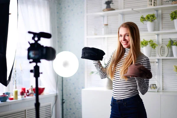 Mode bloggare kvinna i jeans och polotröja visar fashionabla mössor på kameran. Stylist influencer flicka visar trendiga hattar filmar vlog episod för hennes videokanal. Opinionsledare sätter trender. — Stockfoto